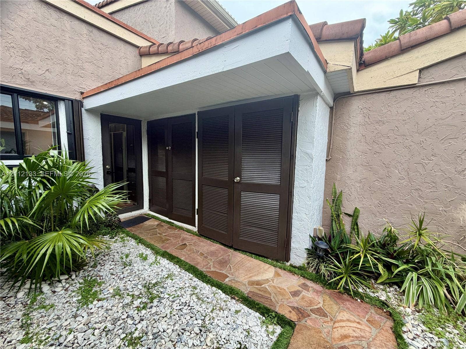 407 Bonnie Brae Way, #22, Hollywood, Hollywood, FL 33021 Stucco exterior featuring dual louvered storage doors, flagstone pathway, and a recessed entryway