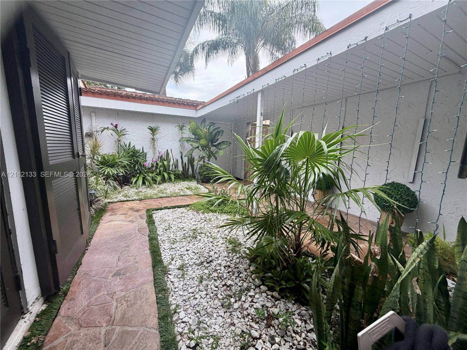 407 Bonnie Brae Way, #22, Hollywood, Hollywood, FL 33021 Enclosed courtyard featuring flagstone walkways, white stone ground cover, mature landscaping, and covered perimeter walkways