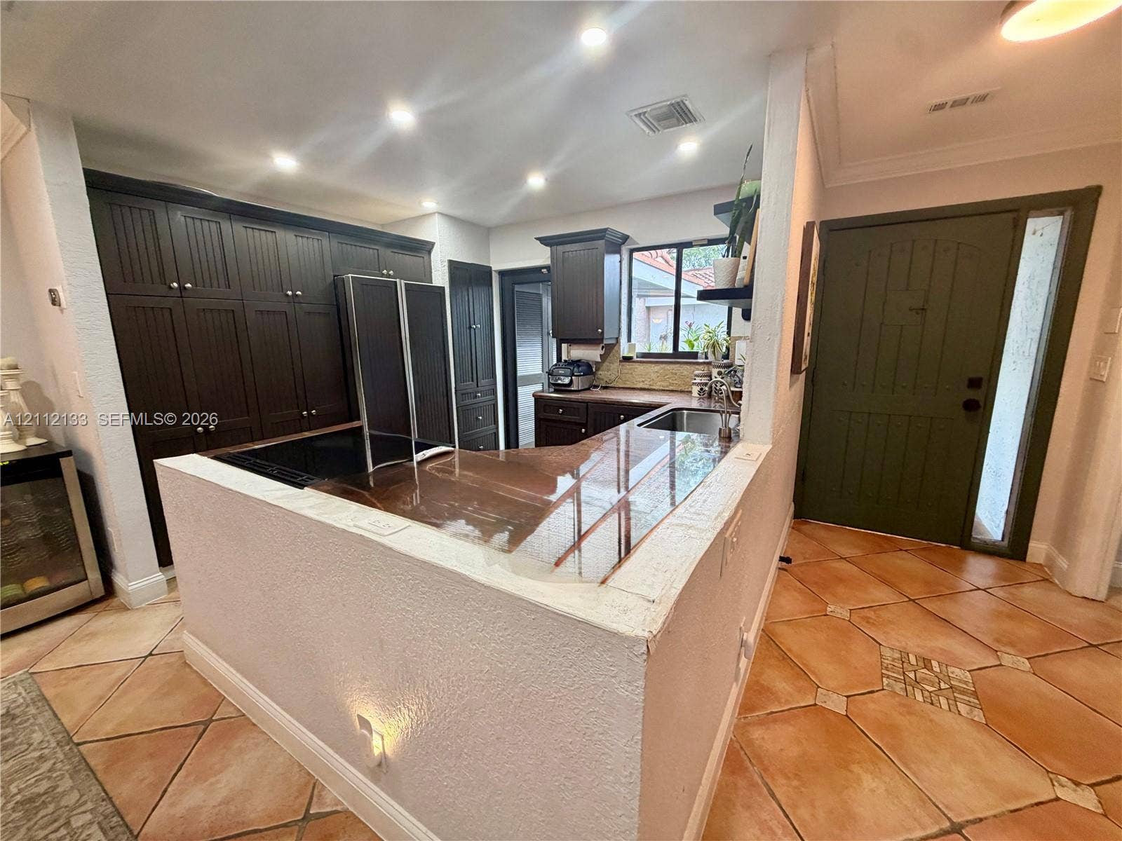 407 Bonnie Brae Way, #22, Hollywood, Hollywood, FL 33021 Kitchen featuring dark-finish cabinetry, a wrap-around stone-surface breakfast bar, recessed lighting, and tile flooring