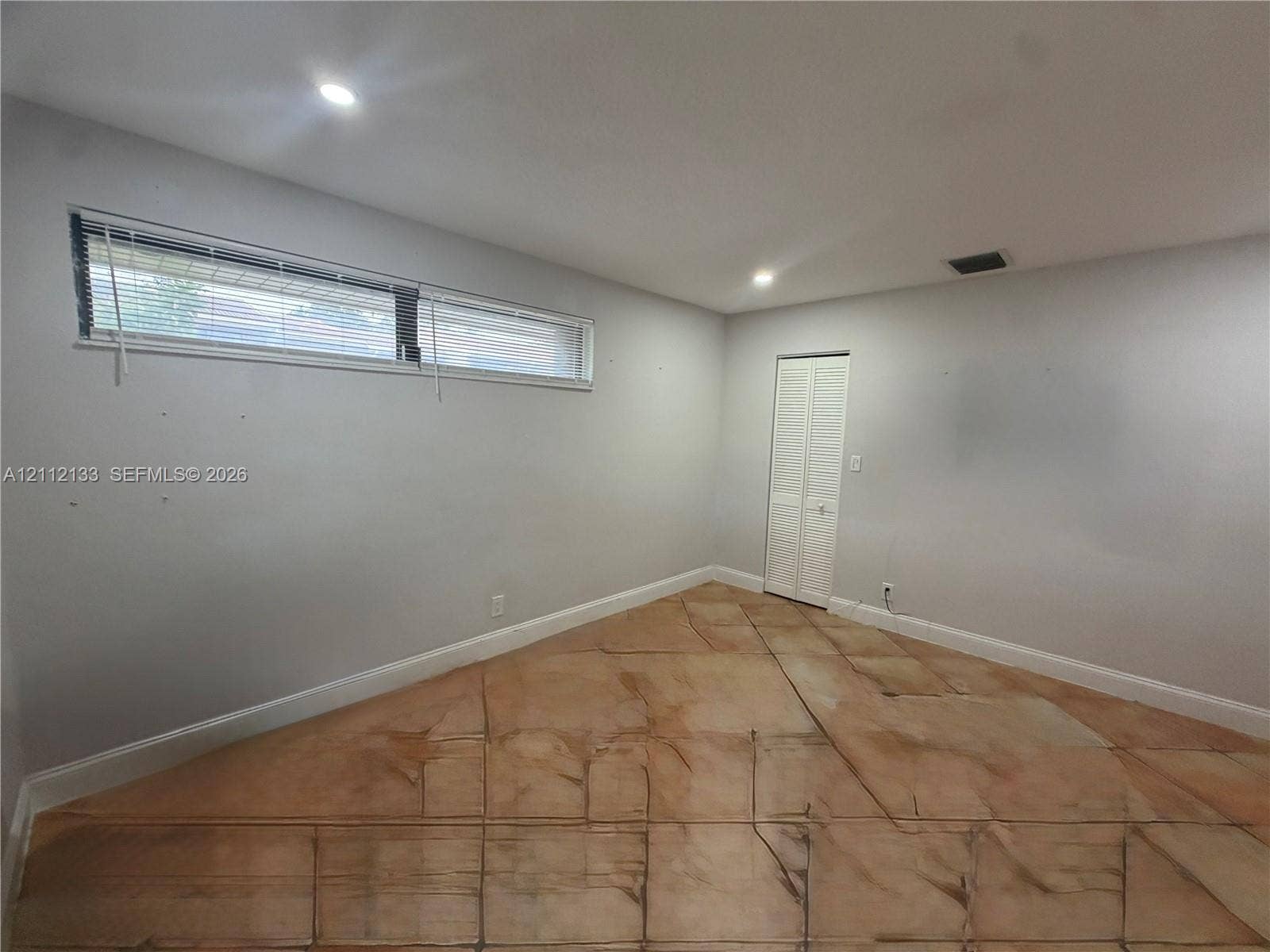 407 Bonnie Brae Way, #22, Hollywood, Hollywood, FL 33021 Neutral-toned interior space featuring light-reflective stone-finish tile flooring, recessed ceiling lighting, and a horizontal window with integrated blinds