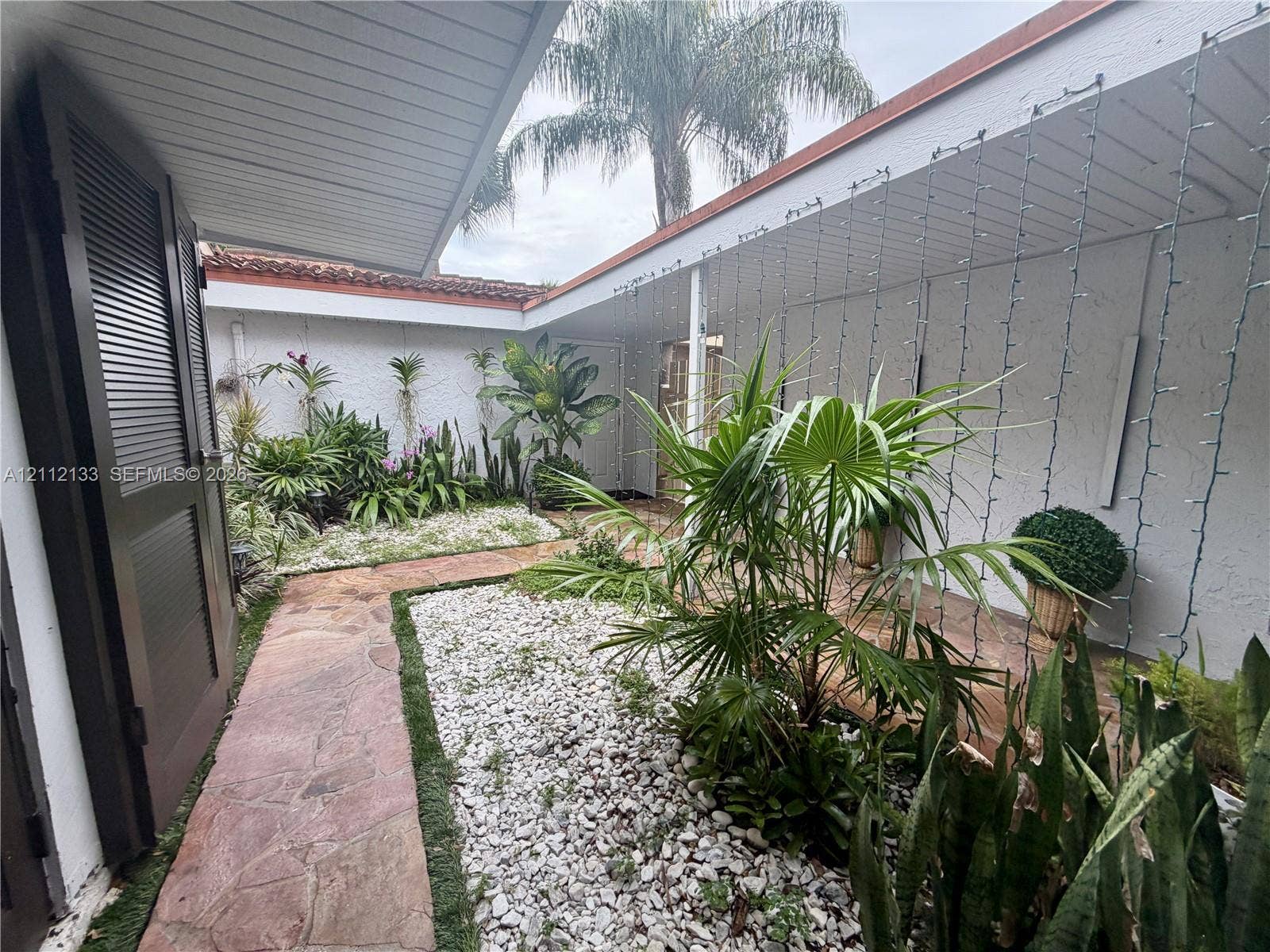 407 Bonnie Brae Way, #22, Hollywood, Hollywood, FL 33021 Enclosed courtyard featuring flagstone pathways, white stone ground cover, mature tropical plantings, and a covered walkway