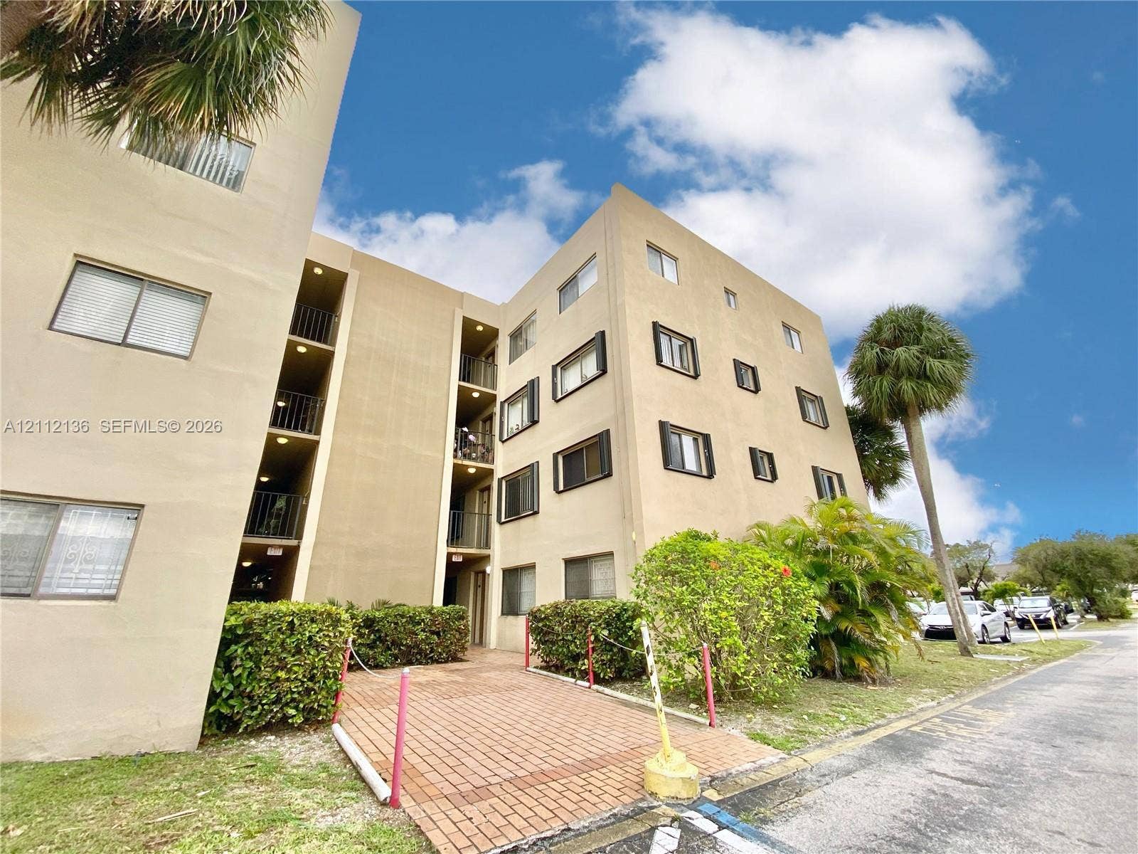 8635 NW 8th Street, #109, Miami, Miami, FL 33126 Multi-story exterior featuring tan stucco facade, brick-paved walkway, and mature landscaping