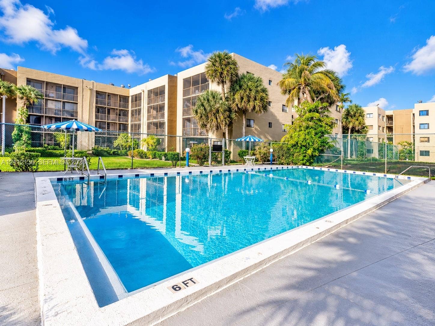 8635 NW 8th Street, #109, Miami, Miami, FL 33126 Outdoor swimming pool featuring a concrete deck, safety fencing, and mature landscaping