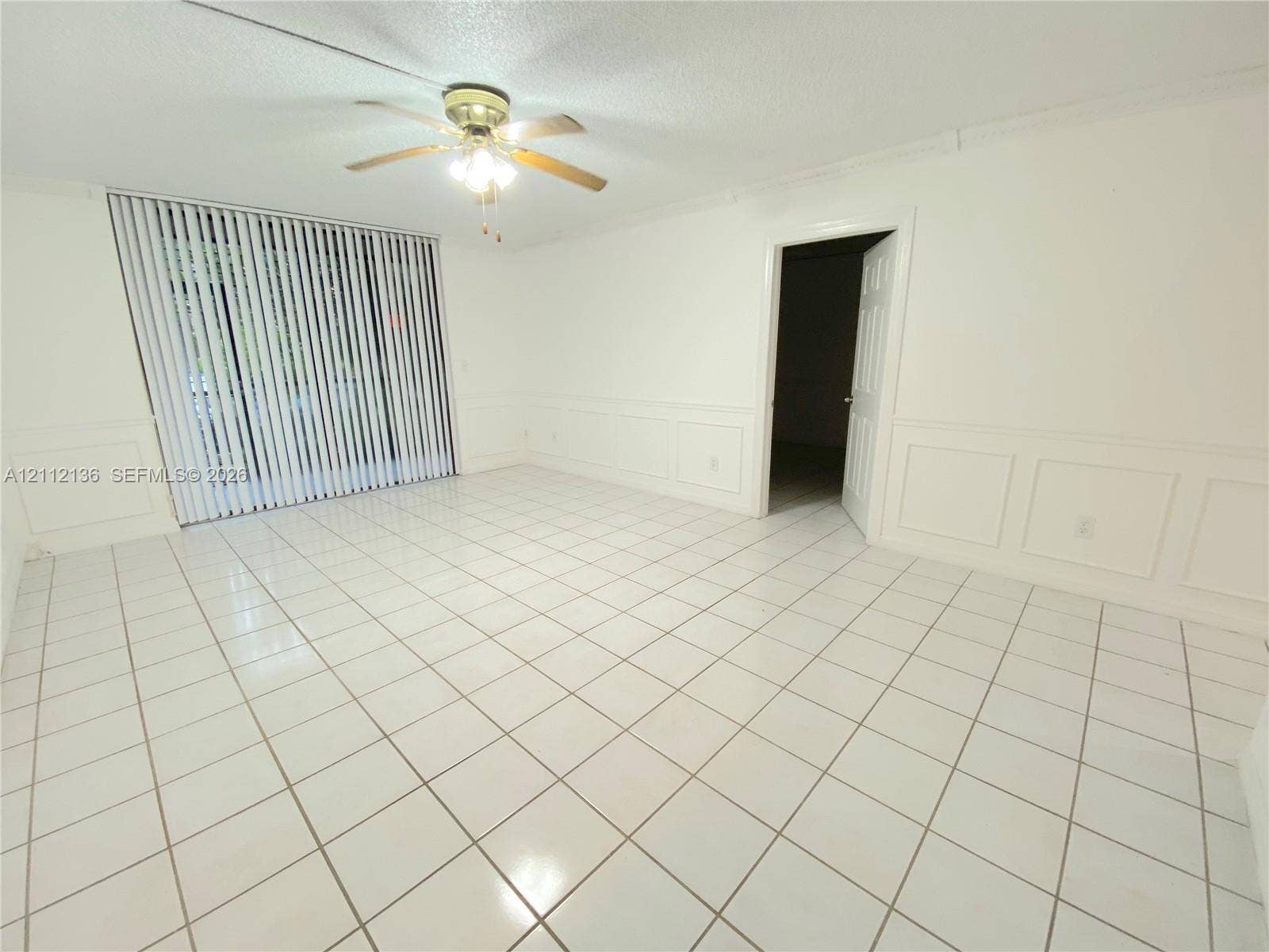 8635 NW 8th Street, #109, Miami, Miami, FL 33126 Ceramic tile flooring, white wainscoting, ceiling-mounted light fixture with fan, and vertical window blinds