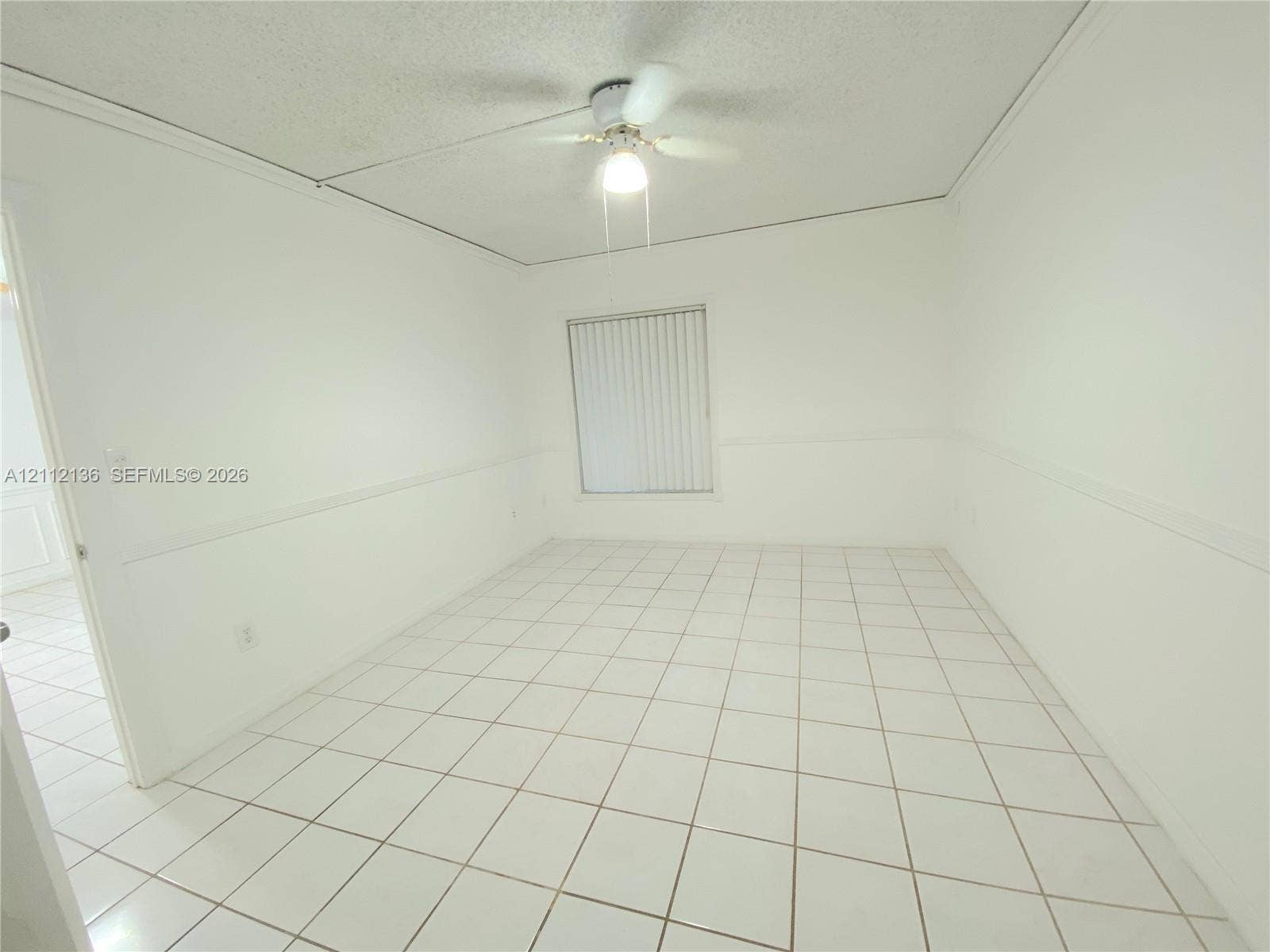 8635 NW 8th Street, #109, Miami, Miami, FL 33126 Room featuring light-colored tile flooring, wall-mounted wainscoting, and a ceiling-mounted light fixture with a fan