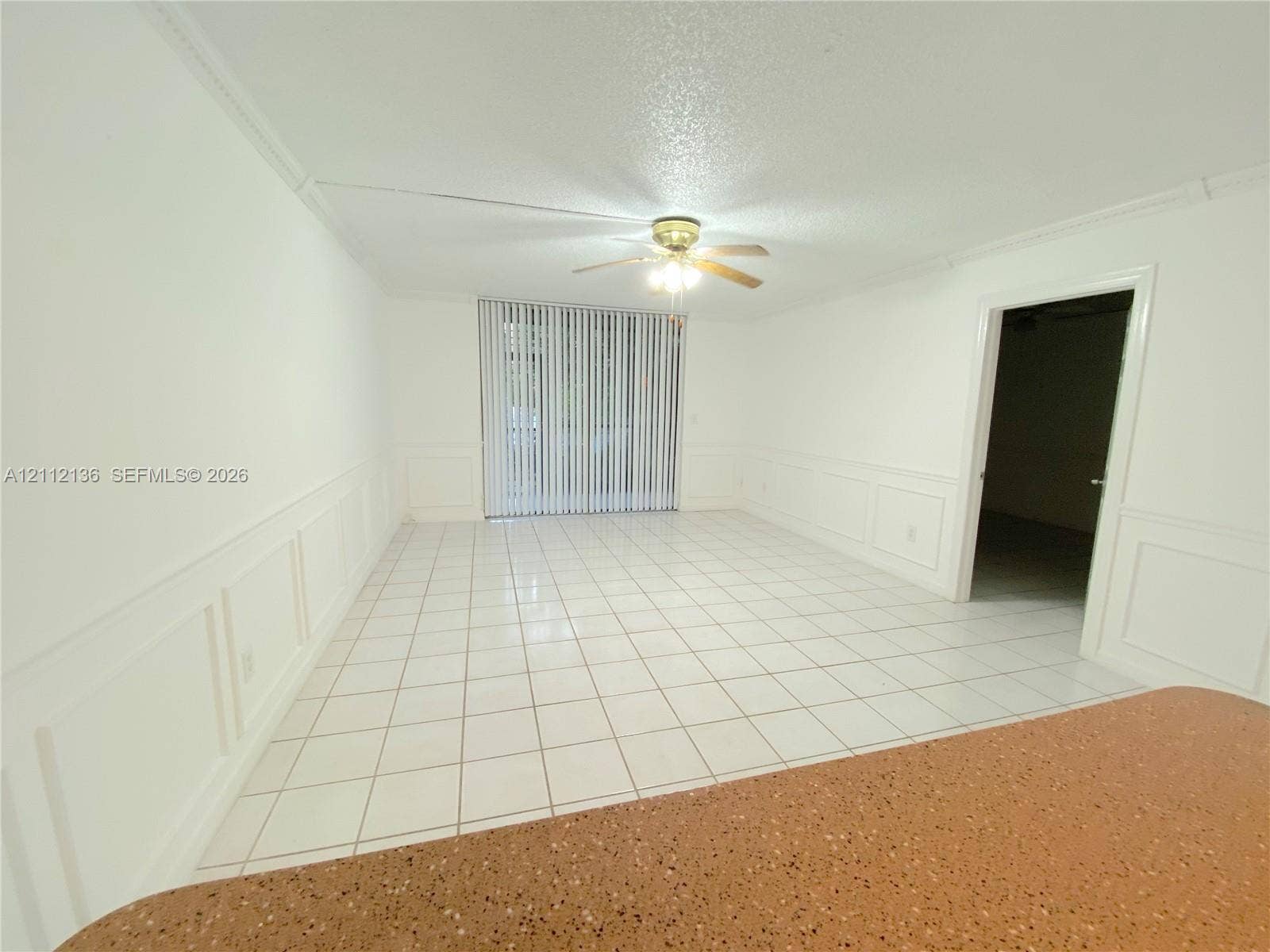 8635 NW 8th Street, #109, Miami, Miami, FL 33126 Interior area featuring white tile flooring, white wainscoting, a ceiling fan with integrated lighting, and sliding glass doors with vertical blinds