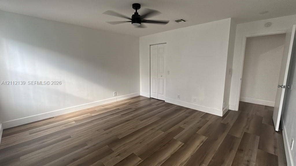 Interior room featuring wood-finish flooring, a matte black ceiling fan, and a bi-fold closet door