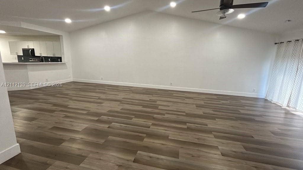 Vaulted ceilings, wood-finish flooring, recessed lighting, and a ceiling fan