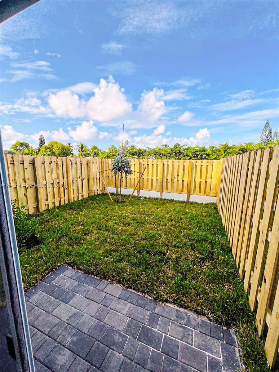 29216 SW 163rd Court, #29216, Homestead, Homestead, FL 33033 Private backyard featuring a paved stone patio, natural grass lawn, and full-perimeter wood fencing