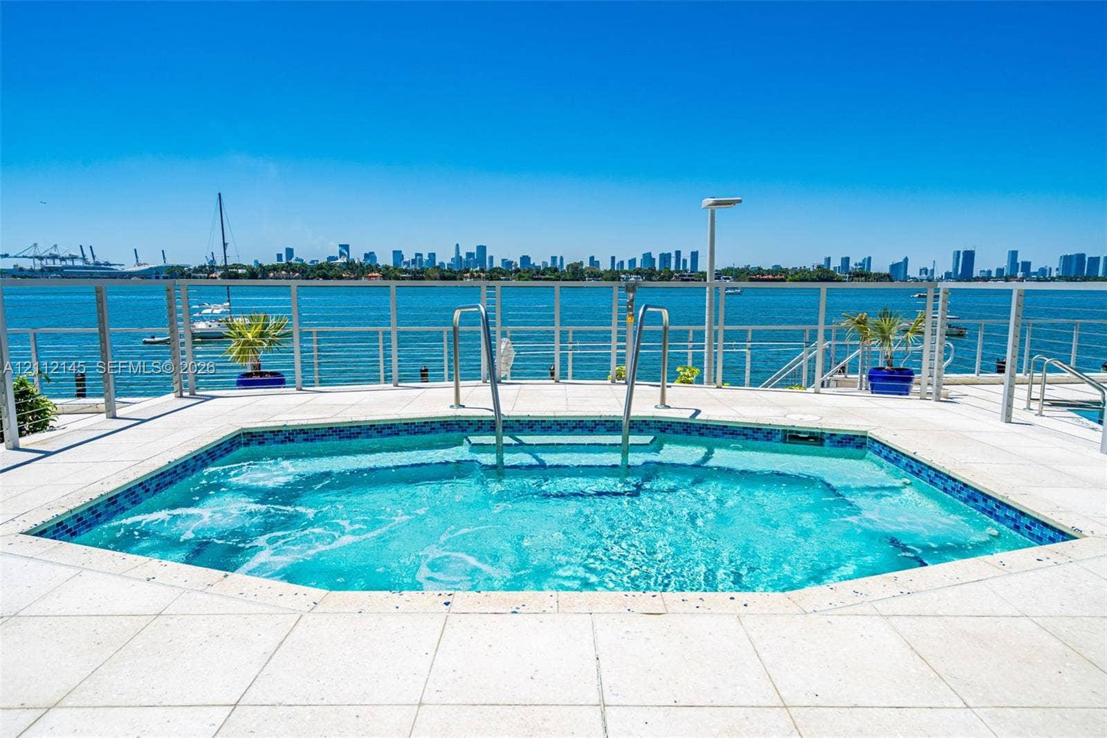 800 West Avenue, #PH-37, Miami Beach, FL 33139 In-ground spa with tile detailing, surrounded by paved stone decking, stainless steel handrails, and a metal perimeter railing