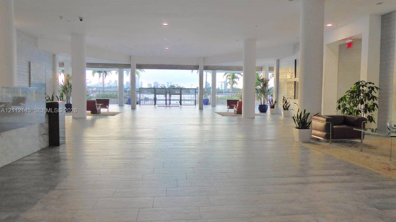800 West Avenue, #PH-37, Miami Beach, FL 33139 Expansive lobby featuring neutral tile flooring, structural columns, recessed lighting, and a glass-paneled entrance with exterior waterfront scenery