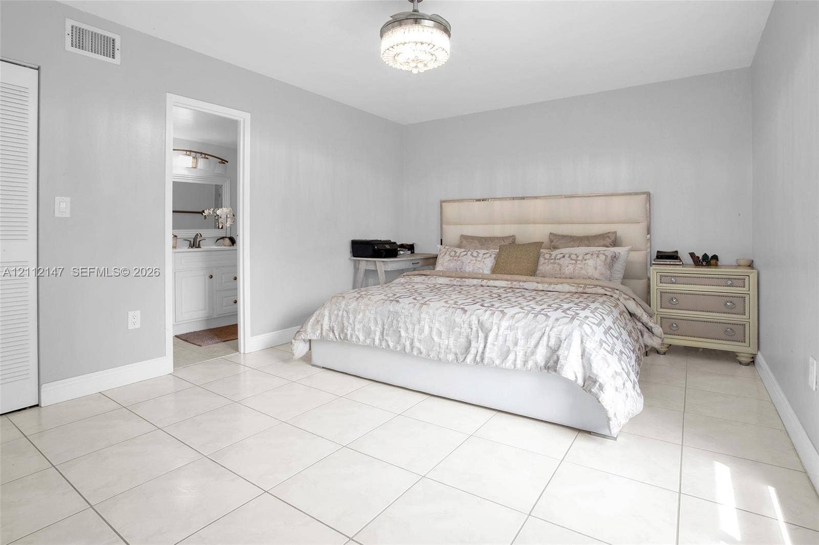 8331 Sands Point Boulevard, #C308, Tamarac, FL 33321 Neutral-toned interior featuring large-format tile flooring, a crystal-accented flush mount ceiling light, and a double-door closet