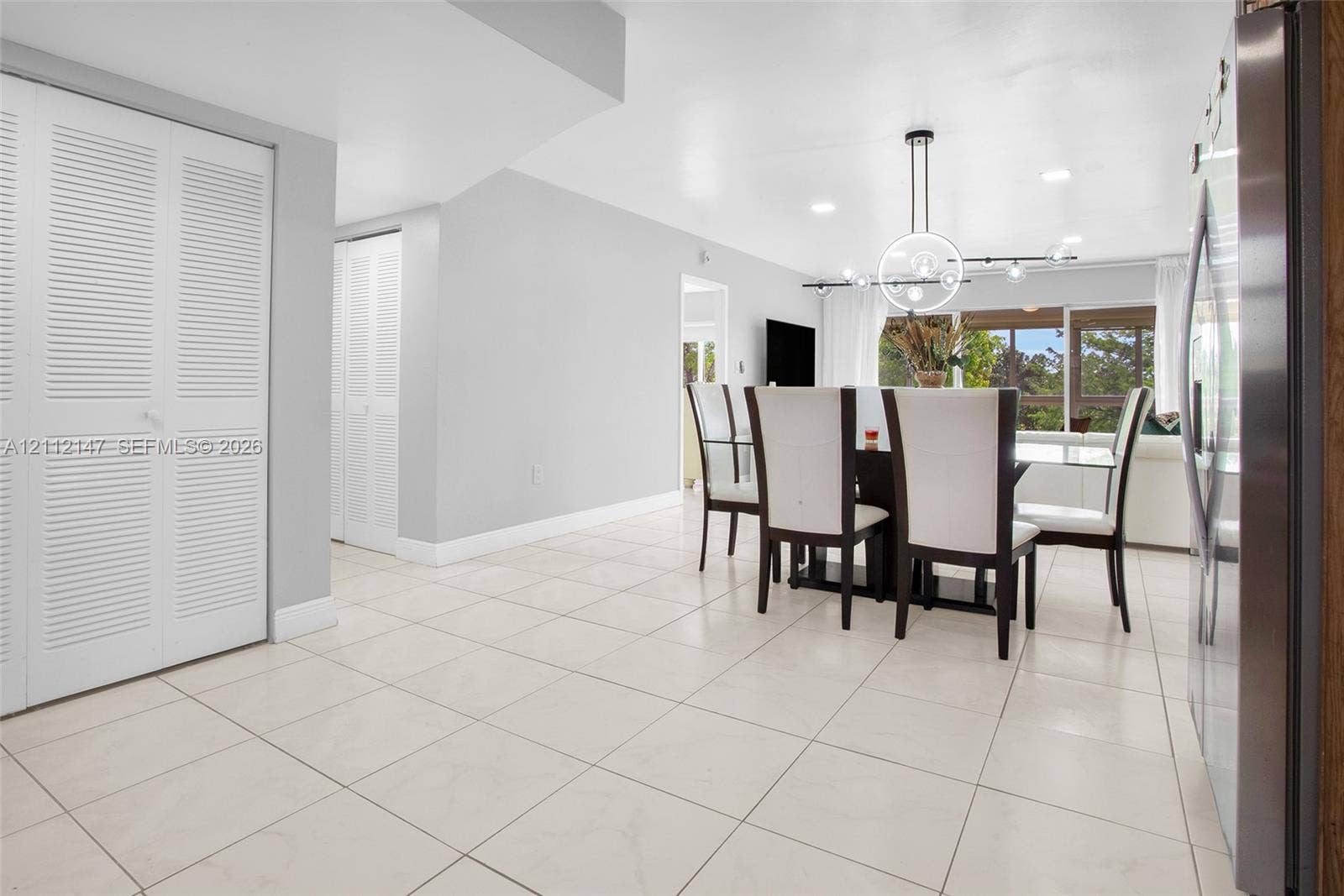 8331 Sands Point Boulevard, #C308, Tamarac, FL 33321 Neutral tile flooring, white louvered-door closets, contemporary circular chandelier, and recessed lighting