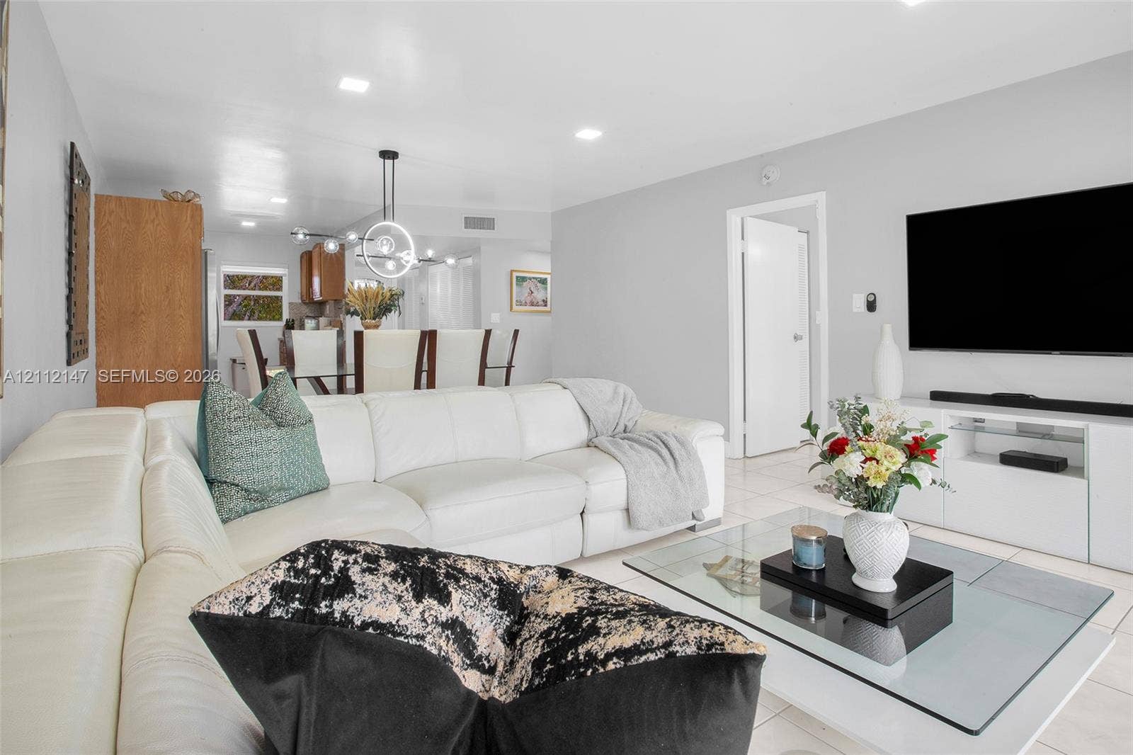 8331 Sands Point Boulevard, #C308, Tamarac, FL 33321 Open-concept interior featuring neutral wall tones, large-format tile flooring, recessed lighting, and a modern circular chandelier fixture