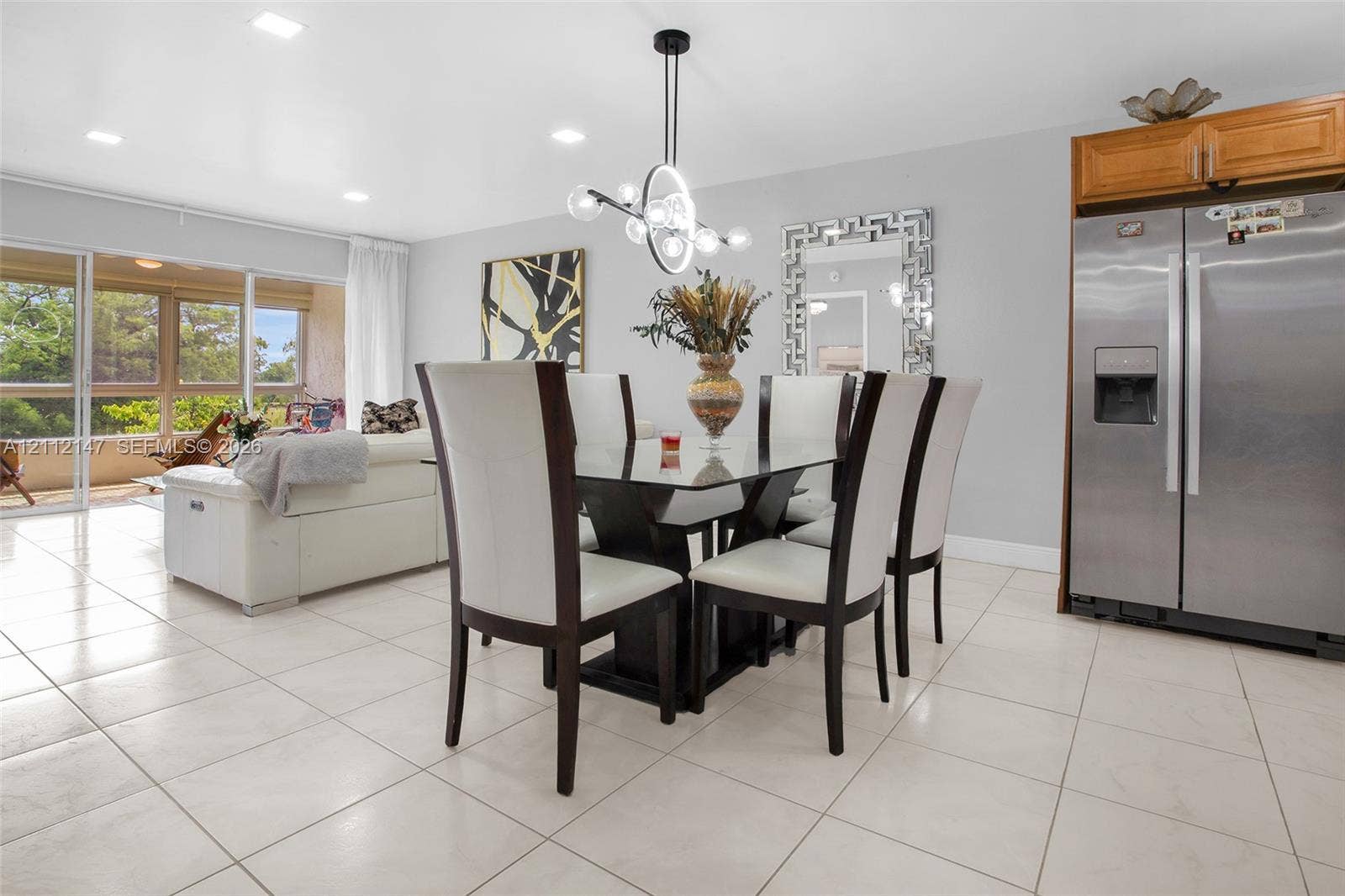 8331 Sands Point Boulevard, #C308, Tamarac, FL 33321 Open-concept area featuring light-toned tile flooring, recessed lighting, a modern multi-light fixture, and large sliding glass doors providing access to the exterior space