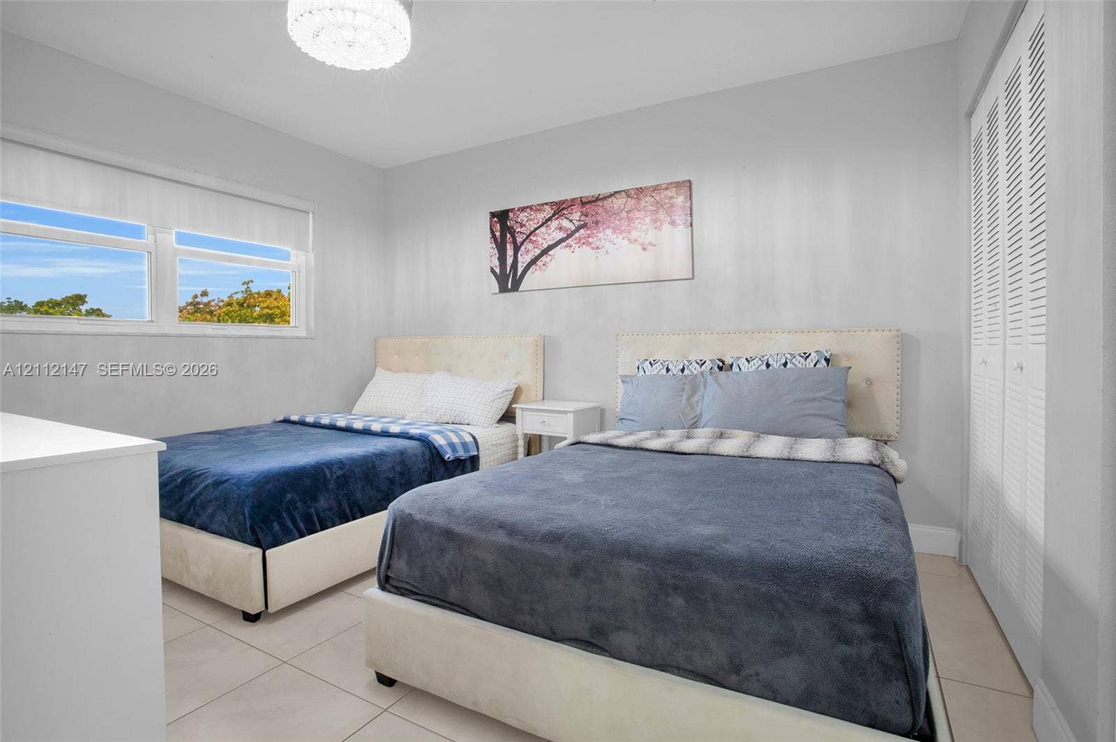 8331 Sands Point Boulevard, #C308, Tamarac, FL 33321 Neutral-toned room featuring large-format tile flooring, double louvered-door closet, multi-pane horizontal window, and contemporary circular flush-mount ceiling light fixture