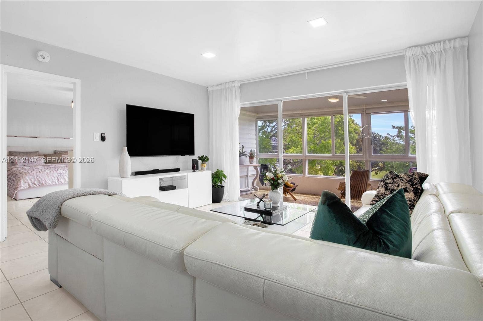8331 Sands Point Boulevard, #C308, Tamarac, FL 33321 Living area featuring large-format tile flooring, recessed lighting, and expansive floor-to-ceiling sliding glass doors opening to a covered patio