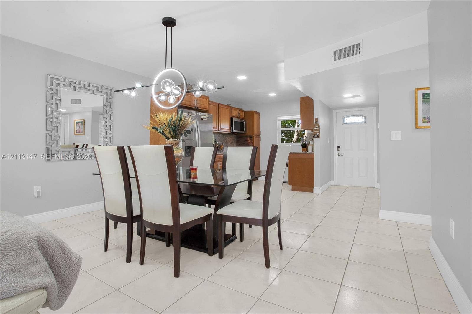 8331 Sands Point Boulevard, #C308, Tamarac, FL 33321 Open concept floor plan with tile flooring, recessed lighting, modern circular chandelier, and kitchen cabinetry