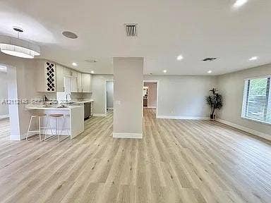 1753 N 16th Court N, Lake Worth, Lake Worth, FL 33460 Open-concept interior featuring wood-finish flooring, a kitchen peninsula with integrated seating, built-in wine storage, recessed lighting, and a modern drum pendant fixture