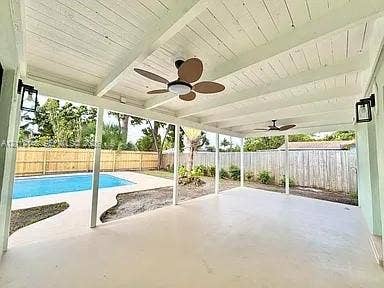 1753 N 16th Court N, Lake Worth, Lake Worth, FL 33460 Covered patio featuring a painted wood-beam ceiling, ceiling fans, wall-mounted lanterns, concrete flooring, and an in-ground swimming pool