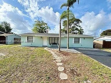 1753 N 16th Court N, Lake Worth, Lake Worth, FL 33460 Single-story exterior featuring light-toned stucco siding, horizontal sliding windows with white shutters, a paved driveway, and a stone-paver walkway