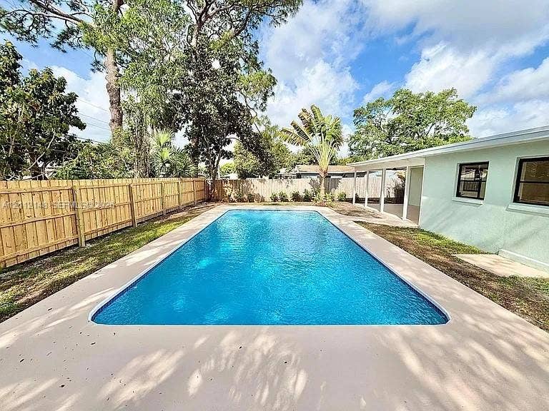 1753 N 16th Court N, Lake Worth, Lake Worth, FL 33460 Rectangular in-ground swimming pool featuring a concrete pool deck, enclosed by a wood privacy fence and covered exterior patio area