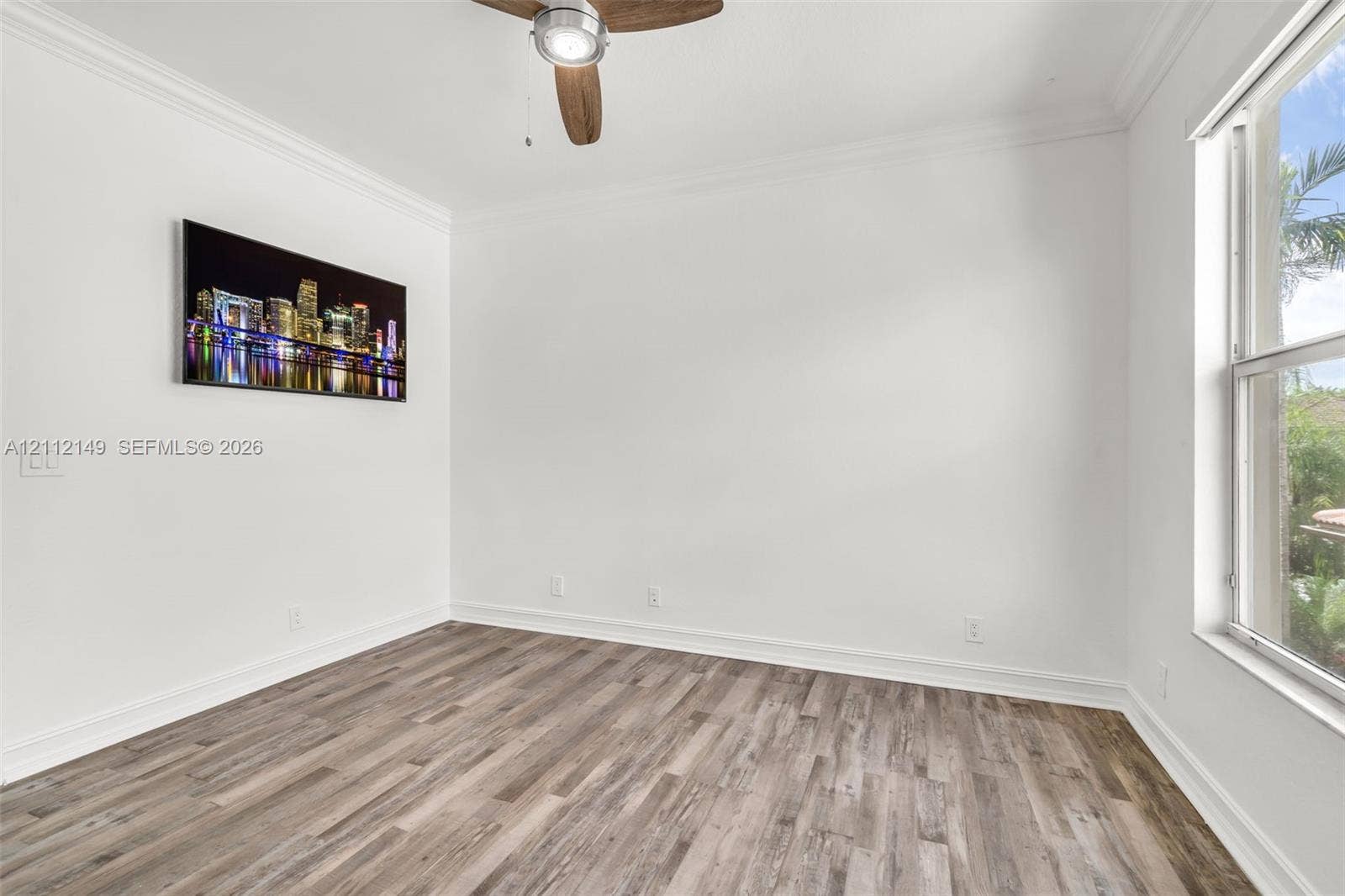 Room featuring wood-finish flooring, crown molding, and a ceiling fan with integrated lighting