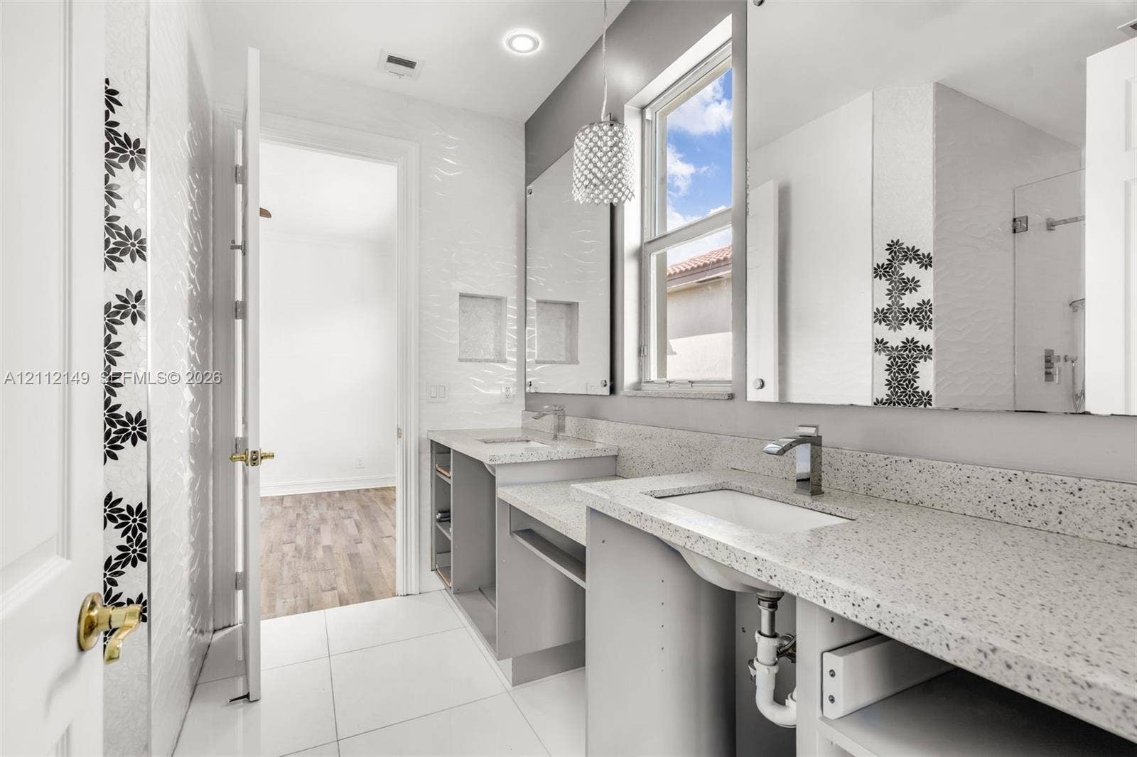 Dual-vanity bathroom featuring speckled stone-finish countertops, undermount sinks, geometric-patterned wall tile accents, and recessed wall shelving