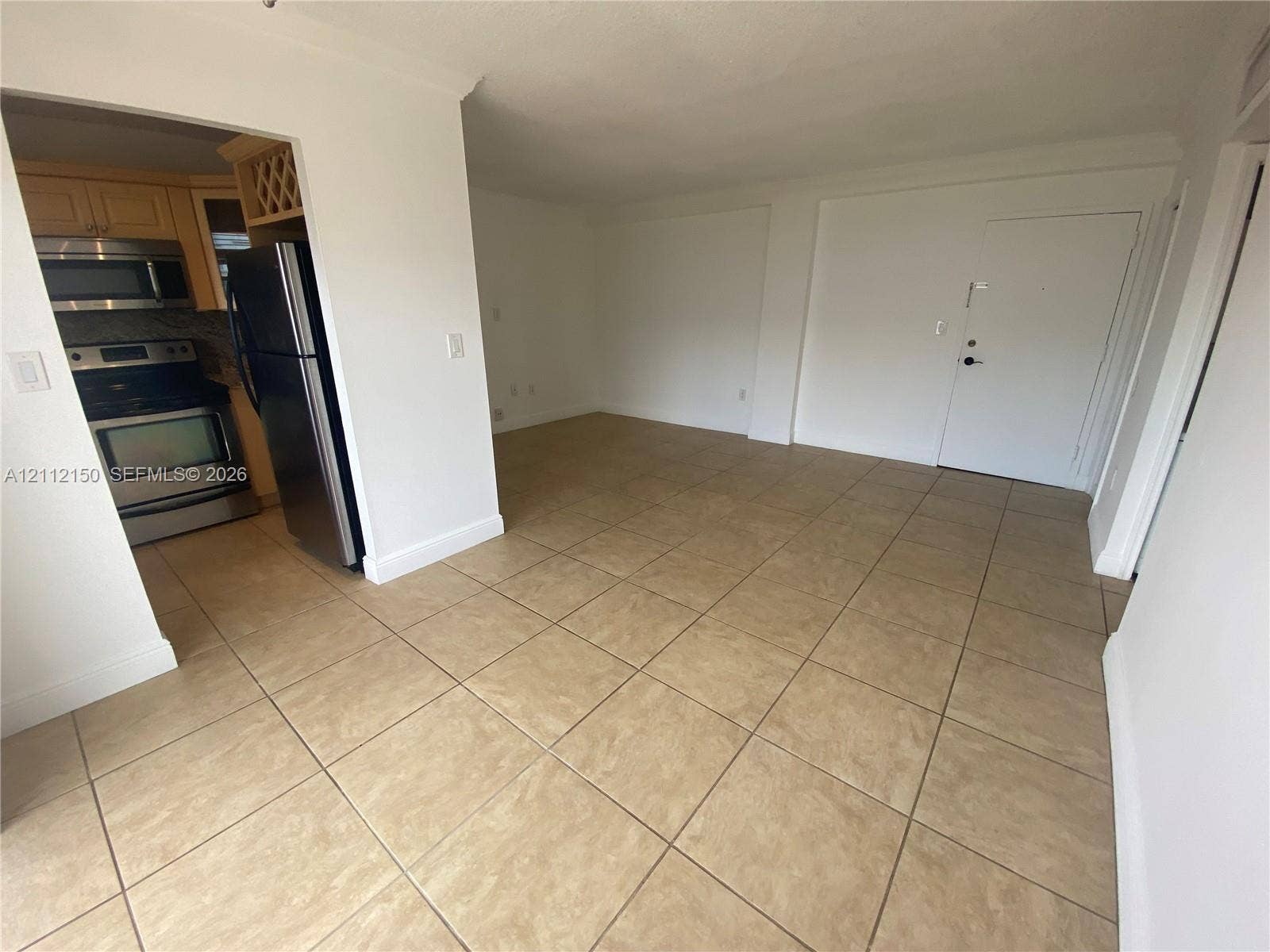 Large-format tile flooring, stainless steel kitchen appliances, and light-tone wood cabinetry