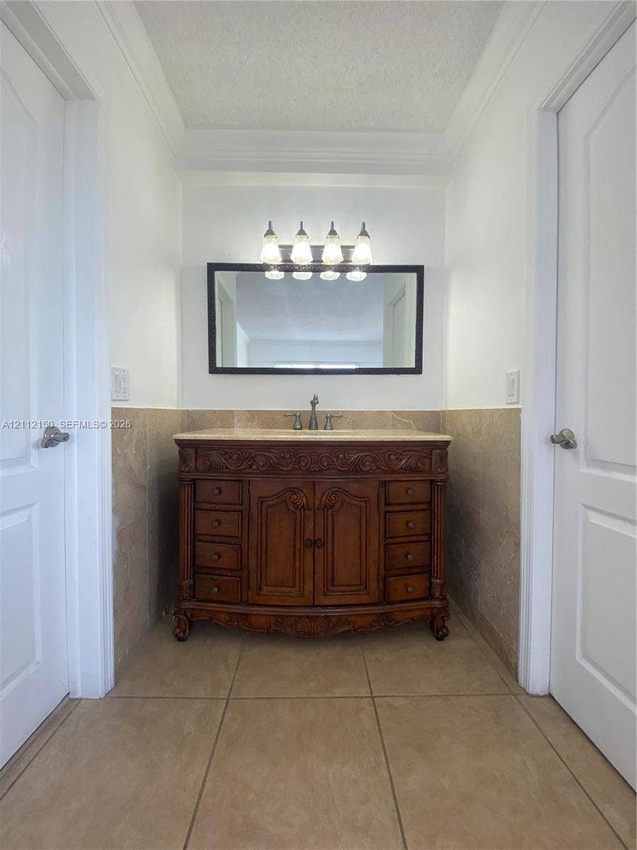 Full-height natural stone wall tile in a neutral finish, integrated corner shelving, curved shower rod, brushed nickel plumbing fixtures, and acrylic soaking tub