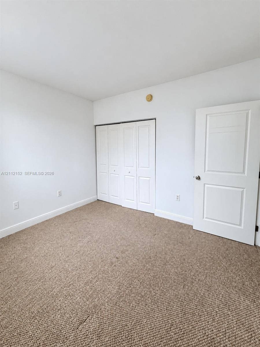 Neutral-toned carpeting, white walls, folding-panel closet doors, and a solid-core two-panel interior door