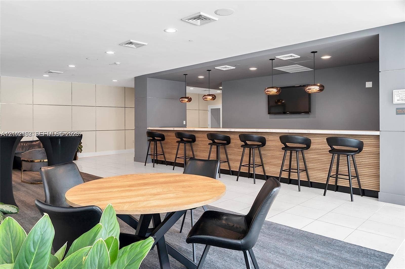 Built-in bar featuring wood-slat paneling, stone countertop, recessed lighting, and modern pendant fixtures