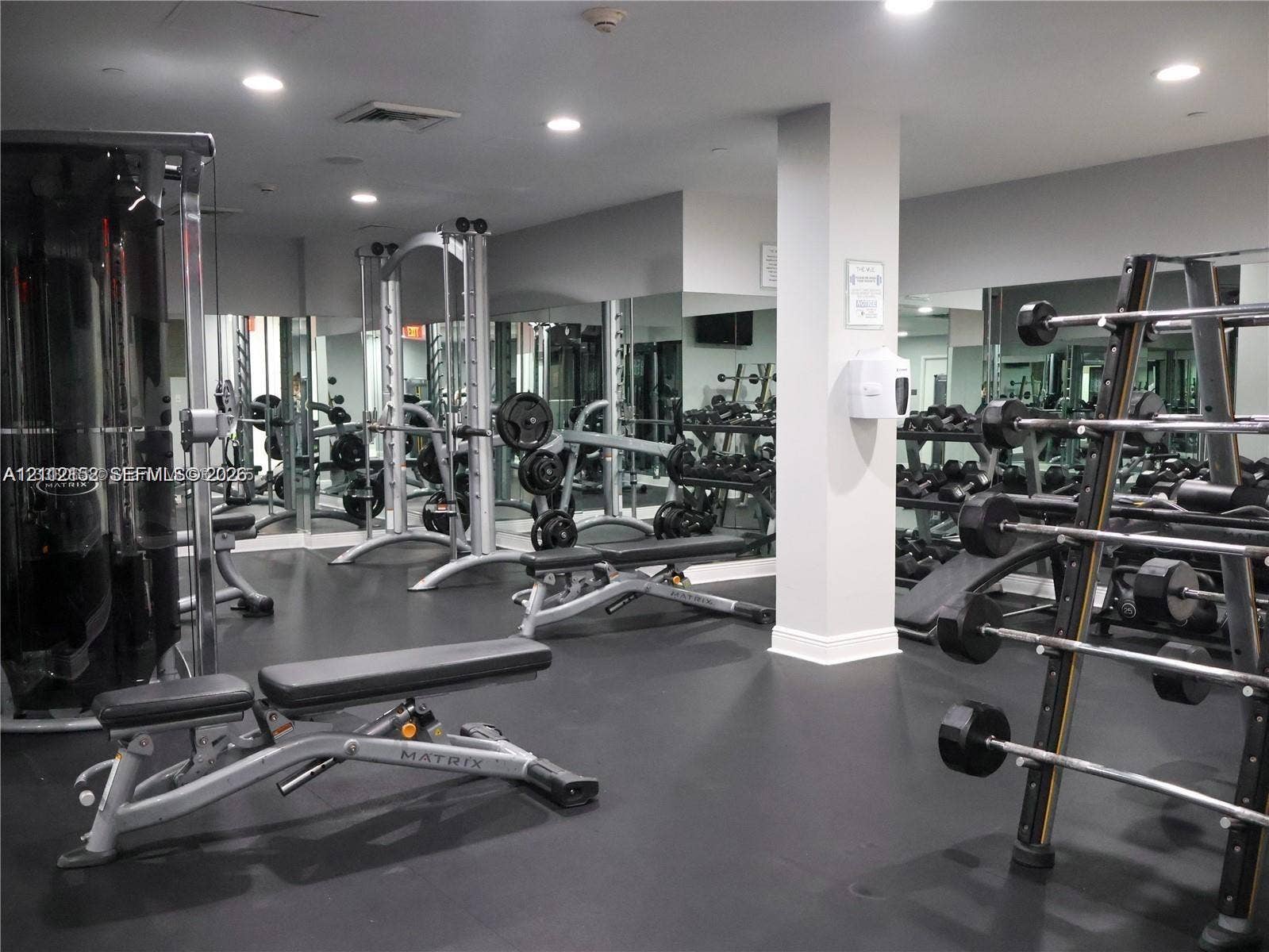 Fitness center featuring rubberized flooring, recessed ceiling lighting, and floor-to-ceiling mirrored walls