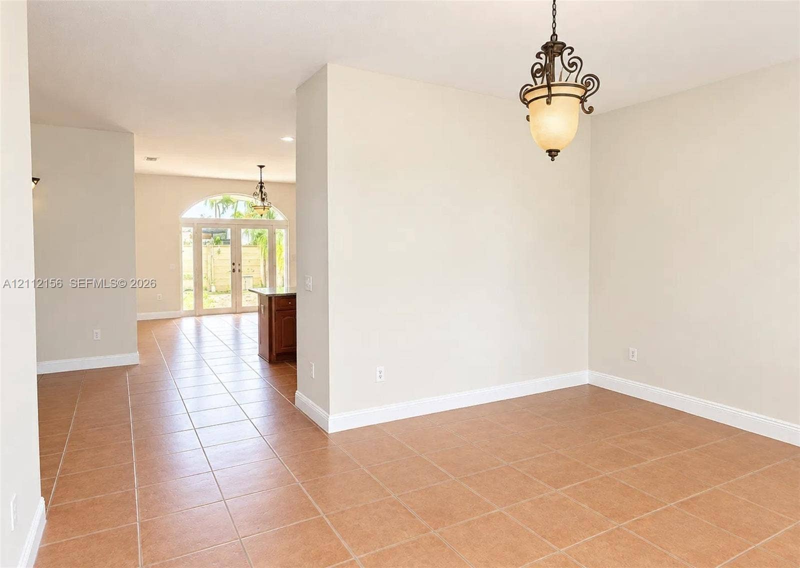 Neutral-toned interior featuring ceramic tile flooring, arched glass double doors, and decorative pendant lighting