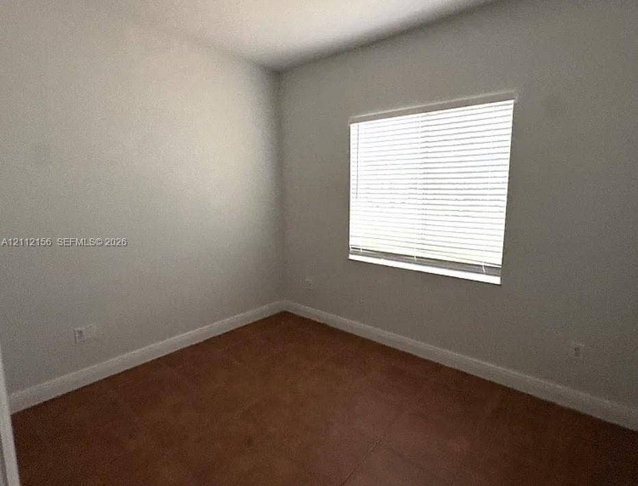 Interior room featuring neutral-toned walls, tile flooring, and a single-pane window with horizontal blinds