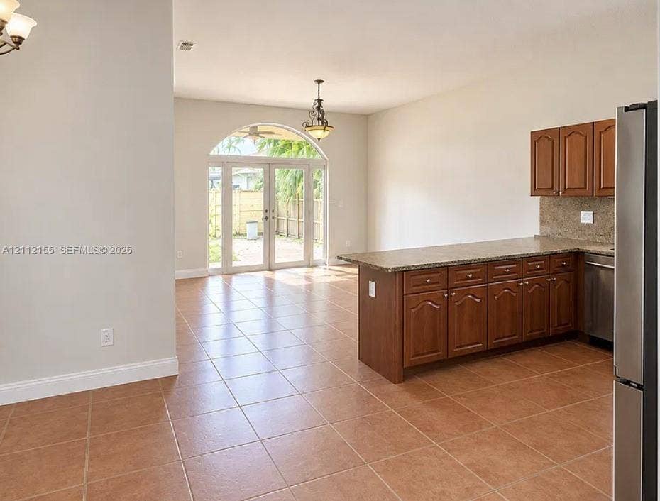 Kitchen featuring wood cabinetry, stone-finish countertops, tile flooring, and arched glass doors
