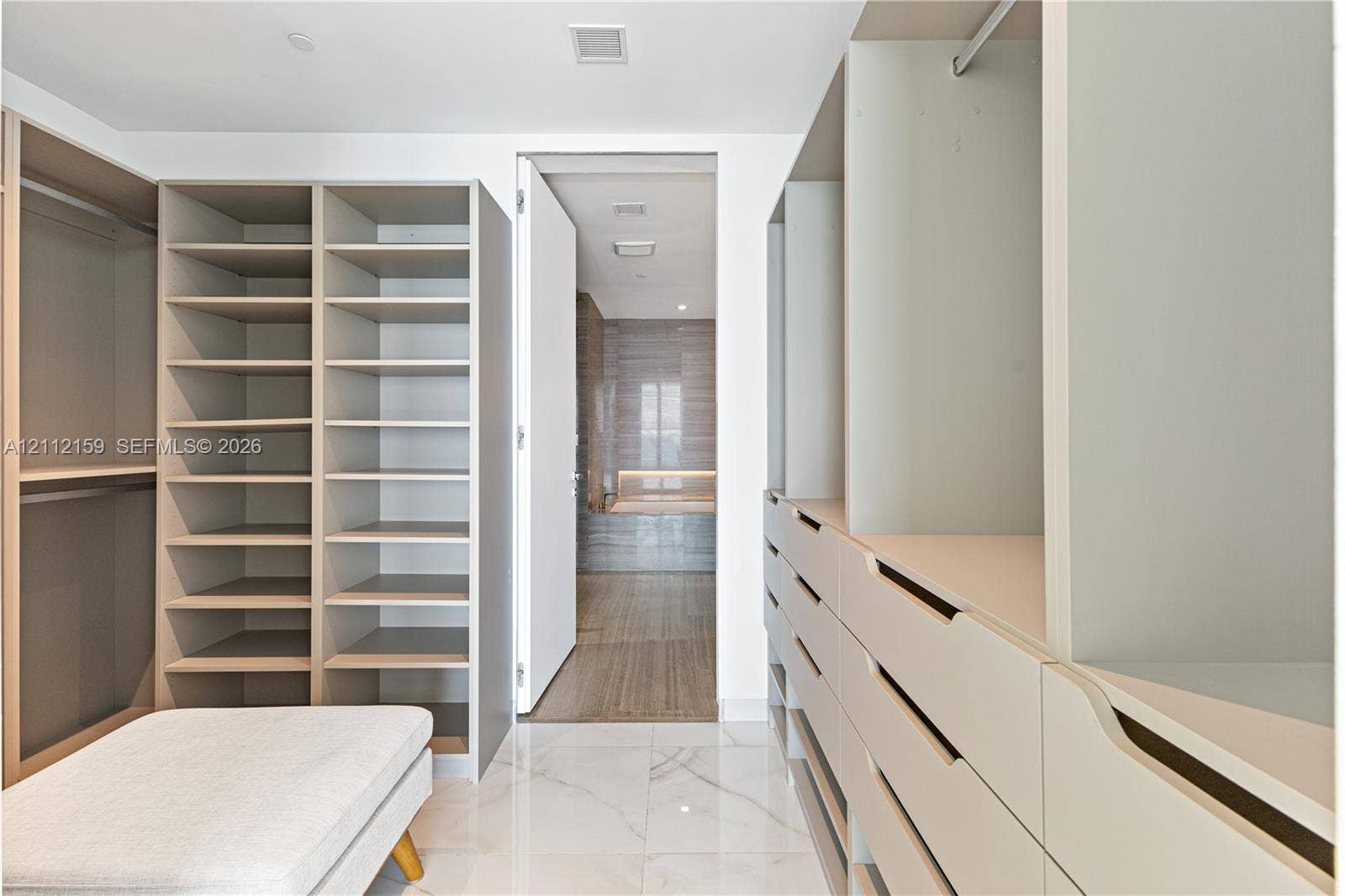 18975 Collins Avenue, #802, Sunny Isles Beach, Sunny Isles Beach, FL 33160 Walk-in closet featuring extensive built-in cabinetry, floor-to-ceiling shelving, recessed drawer units, and polished stone-finish flooring