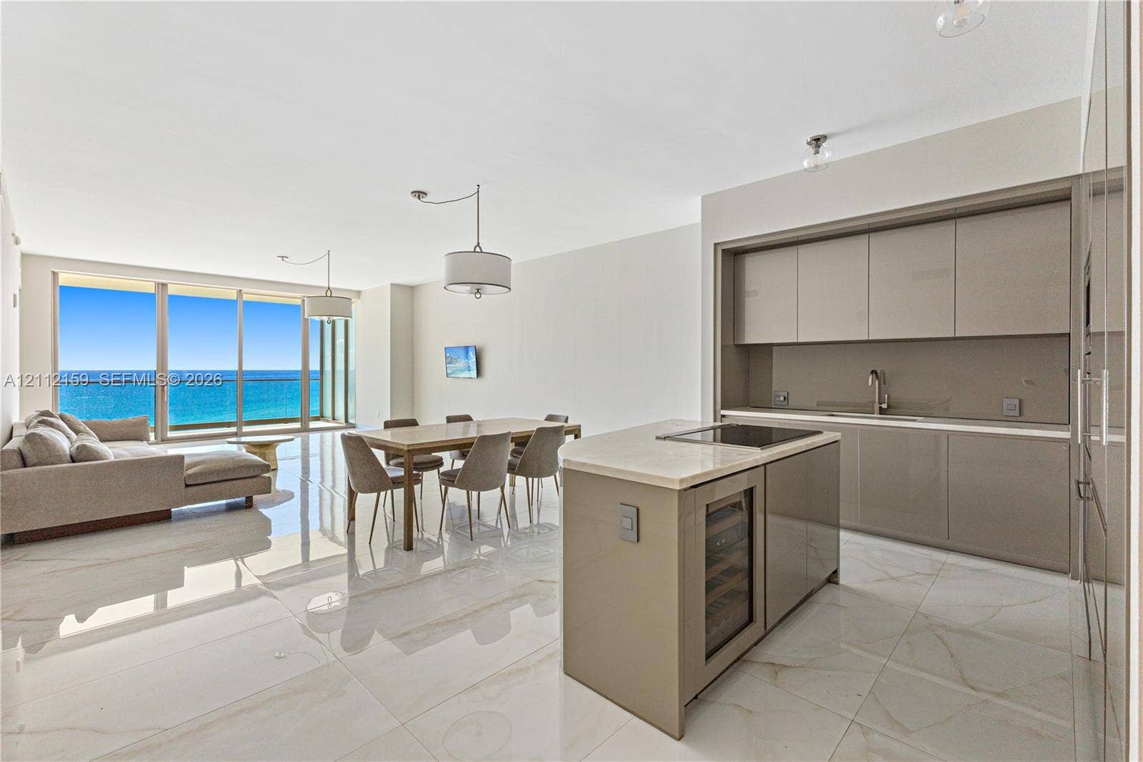 18975 Collins Avenue, #802, Sunny Isles Beach, Sunny Isles Beach, FL 33160 Open-concept interior featuring light-toned flooring, high-gloss flat-panel cabinetry, a stone-topped kitchen island with a built-in wine cooler, recessed lighting, and floor-to-ceiling glass sliding doors