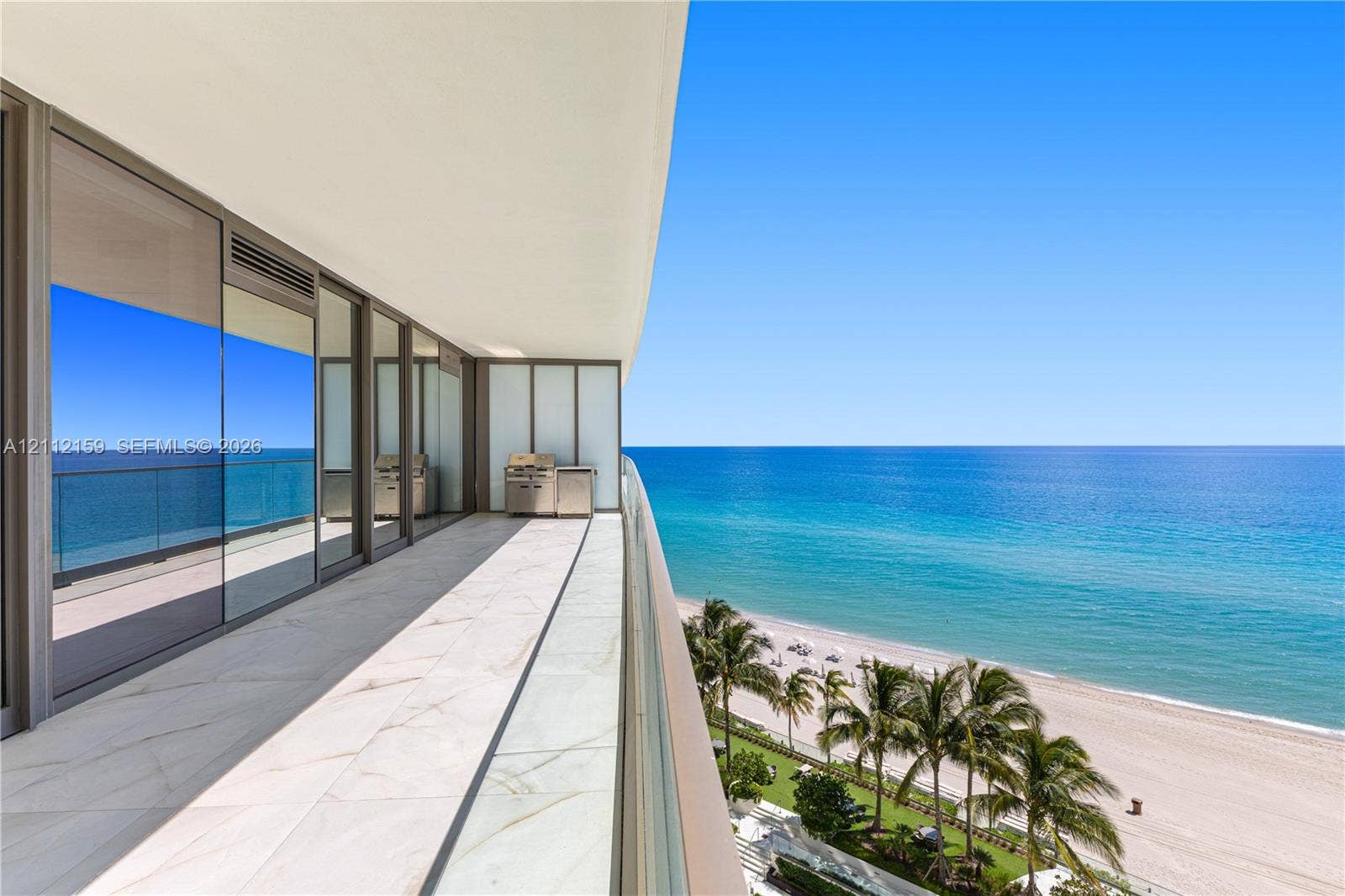 18975 Collins Avenue, #802, Sunny Isles Beach, Sunny Isles Beach, FL 33160 Expansive balcony featuring large-format tile flooring, a glass panel railing, built-in stainless steel outdoor kitchen equipment, and full-height sliding glass doors