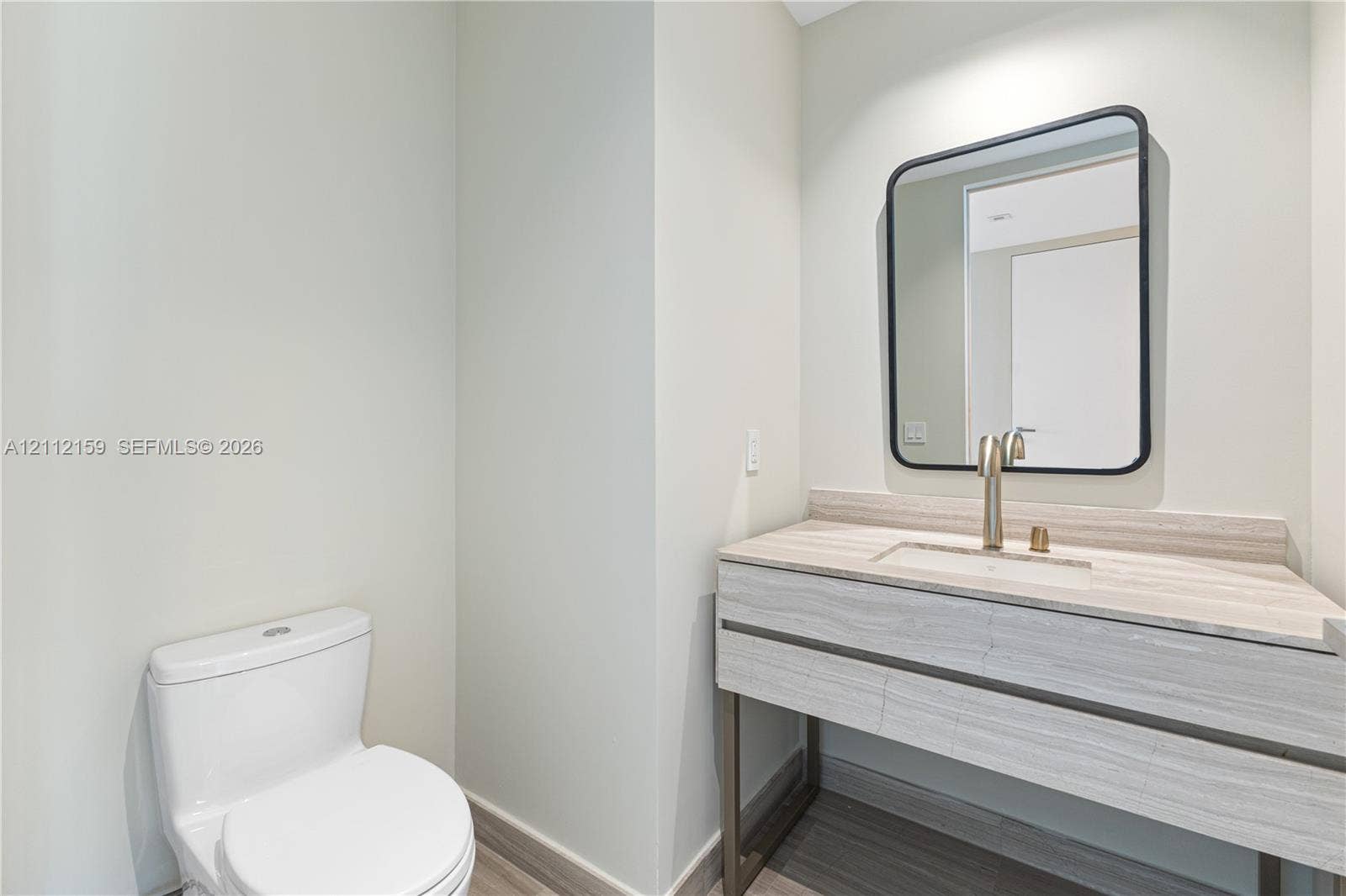 18975 Collins Avenue, #802, Sunny Isles Beach, Sunny Isles Beach, FL 33160 Modern vanity featuring a stone-finish countertop, integrated sink, metal-frame base, rounded rectangular mirror, and brushed-finish faucet