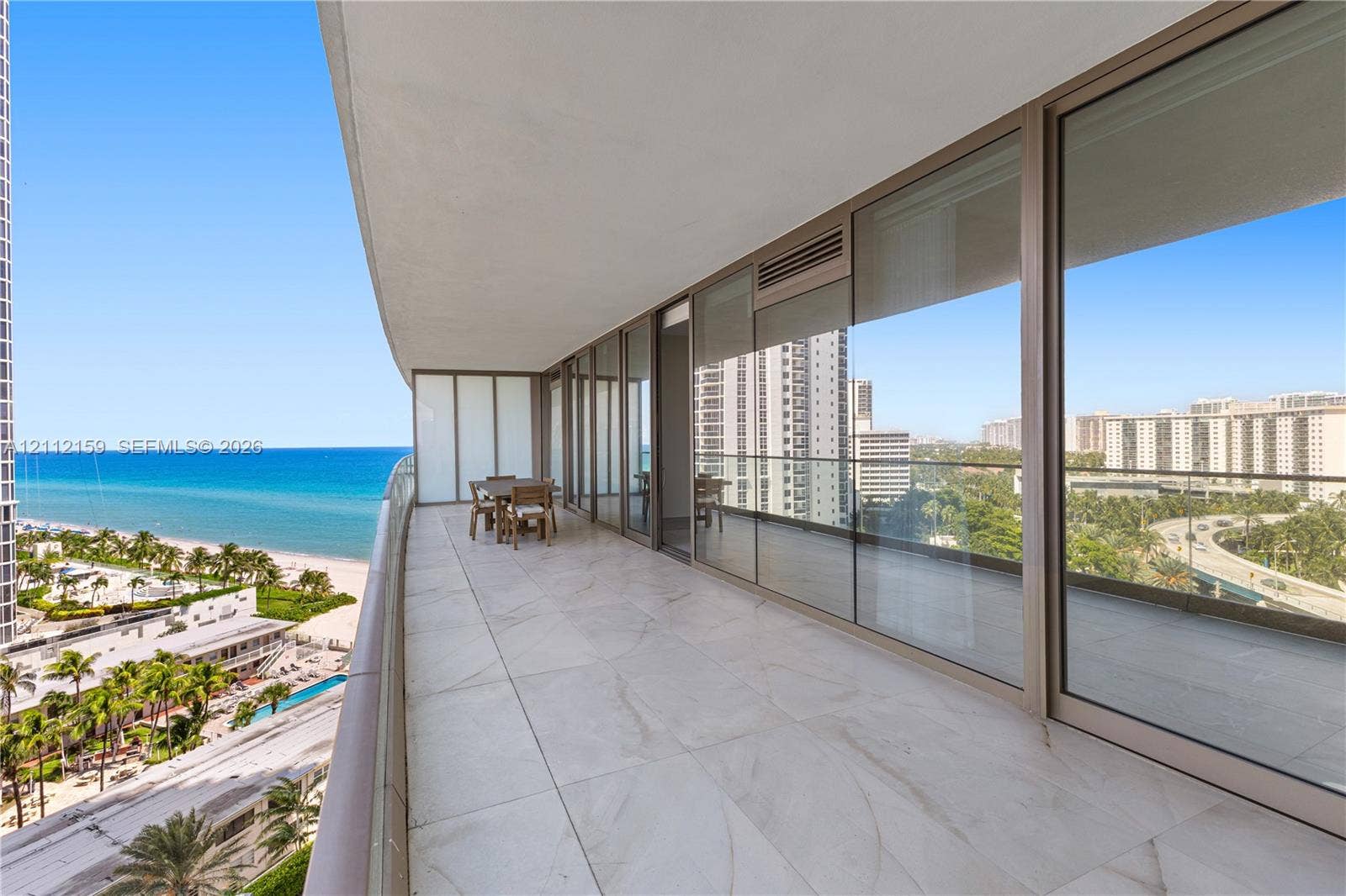 18975 Collins Avenue, #802, Sunny Isles Beach, Sunny Isles Beach, FL 33160 Expansive covered balcony featuring large-format tile flooring, floor-to-ceiling glass paneling, and metallic framing