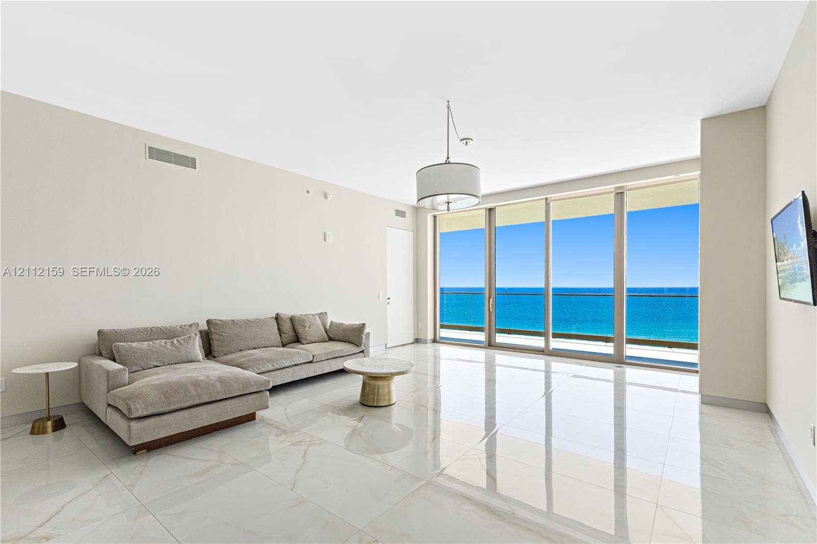 18975 Collins Avenue, #802, Sunny Isles Beach, Sunny Isles Beach, FL 33160 Polished stone flooring, floor-to-ceiling glass sliding doors, private balcony, and pendant lighting