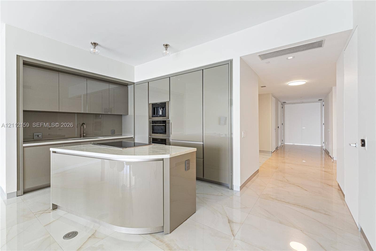 18975 Collins Avenue, #802, Sunny Isles Beach, Sunny Isles Beach, FL 33160 Kitchen featuring high-gloss cabinetry, stone-surface center island with integrated cooktop, built-in double wall oven, and large-format tile flooring