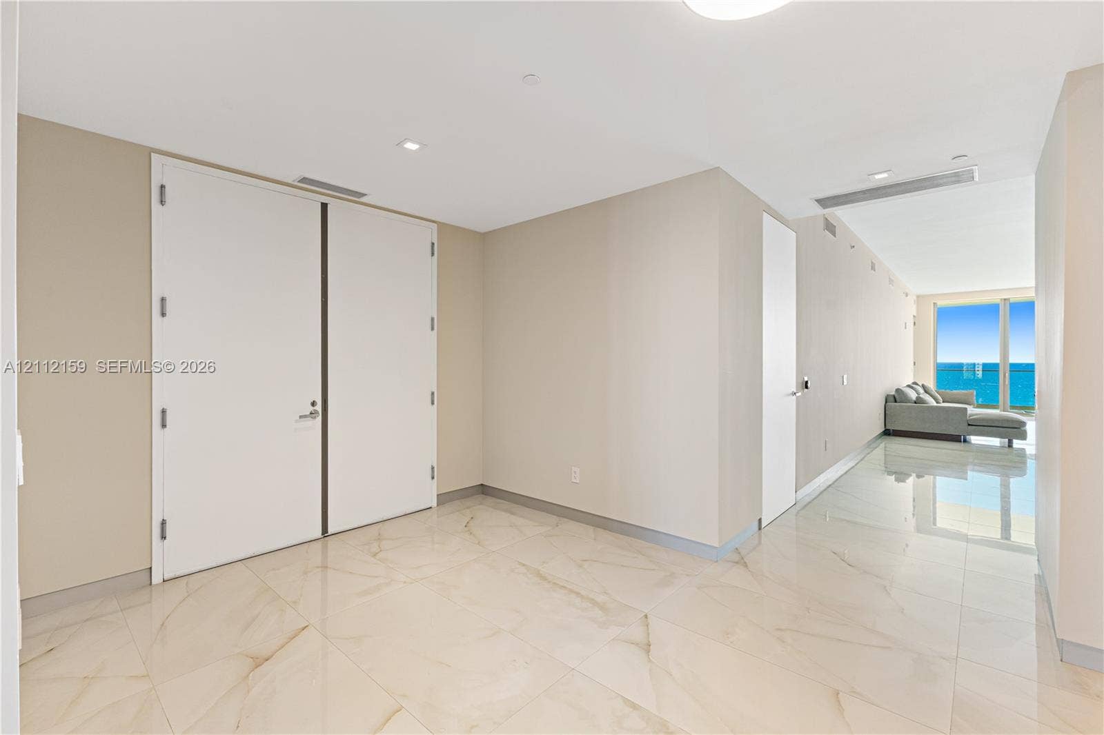 18975 Collins Avenue, #802, Sunny Isles Beach, Sunny Isles Beach, FL 33160 Large-format polished tile flooring with natural stone-style veining, high ceilings with recessed lighting, and expansive floor-to-ceiling windows featuring water scenery