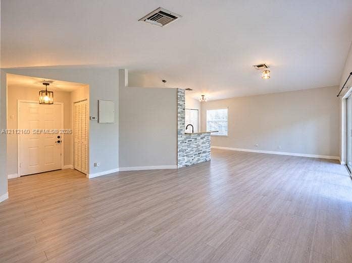 Open floor plan featuring wood-finish flooring, a stacked stone accent wall, recessed lighting, and a six-panel entry door