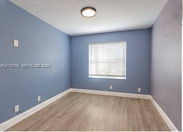Room featuring wood-finish flooring, a single-window configuration with horizontal blinds, and a central flush-mount ceiling light fixture