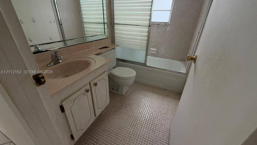 309 Fanshaw H, #309, Boca Raton, FL 33434 Bathroom featuring a vanity with integrated sink, large wall-mounted mirror, mosaic tile flooring, and a bathtub with sliding glass doors