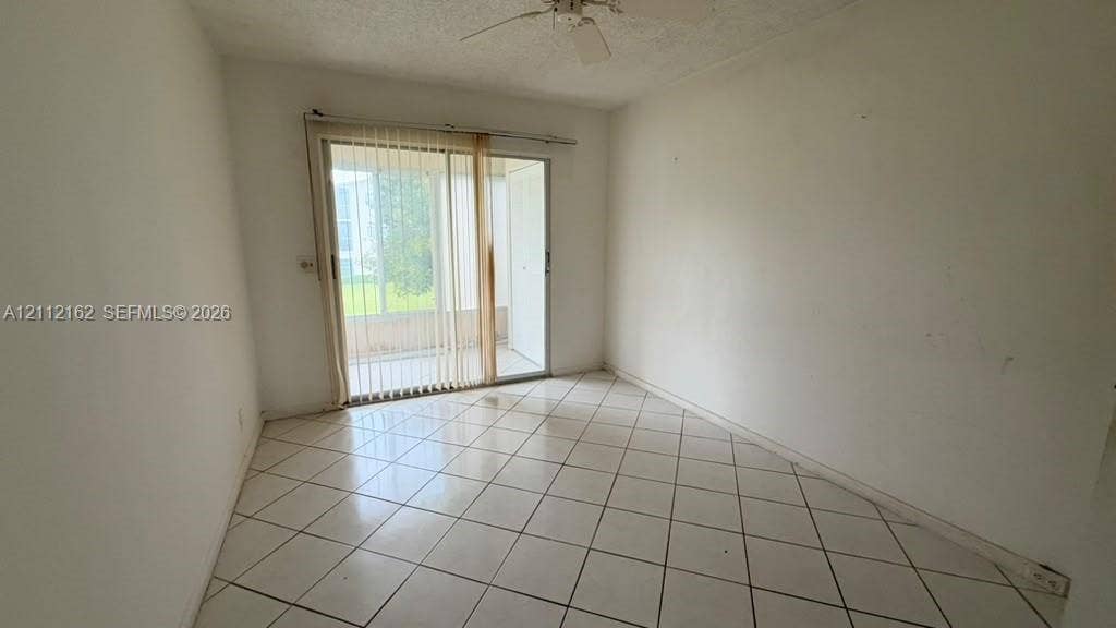 309 Fanshaw H, #309, Boca Raton, FL 33434 Room featuring neutral wall finishes, tile flooring laid on a diagonal pattern, sliding glass doors, and a ceiling-mounted fan