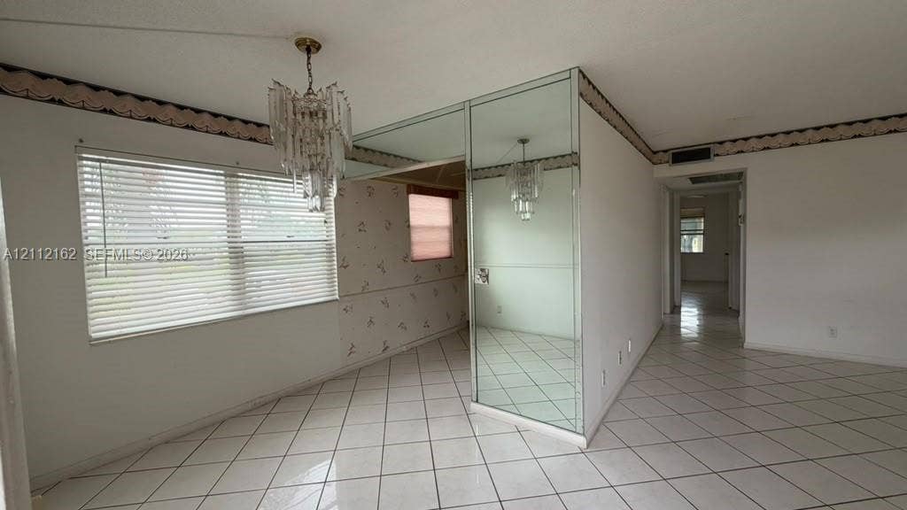 309 Fanshaw H, #309, Boca Raton, FL 33434 Interior space featuring white tile flooring, floor-to-ceiling mirrored wall cladding, and a multi-tiered crystal chandelier