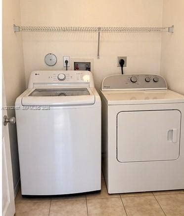 Laundry area featuring tile flooring, built-in wire shelving, and dedicated utility hookups